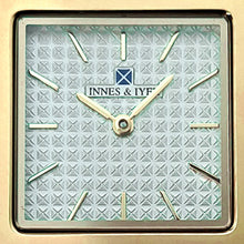 Square watch's clock face with hands in gold colour.